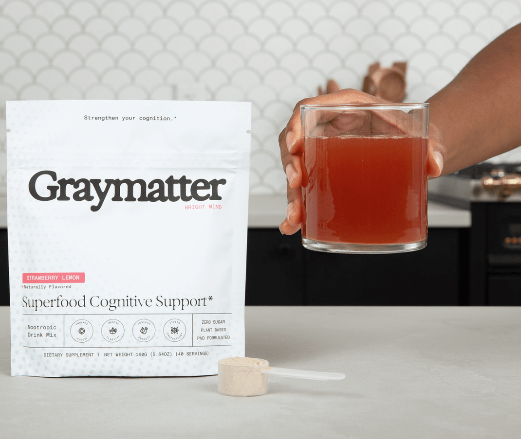 Package of Graymatter drink mix and glass of strawberry lemon beverage.